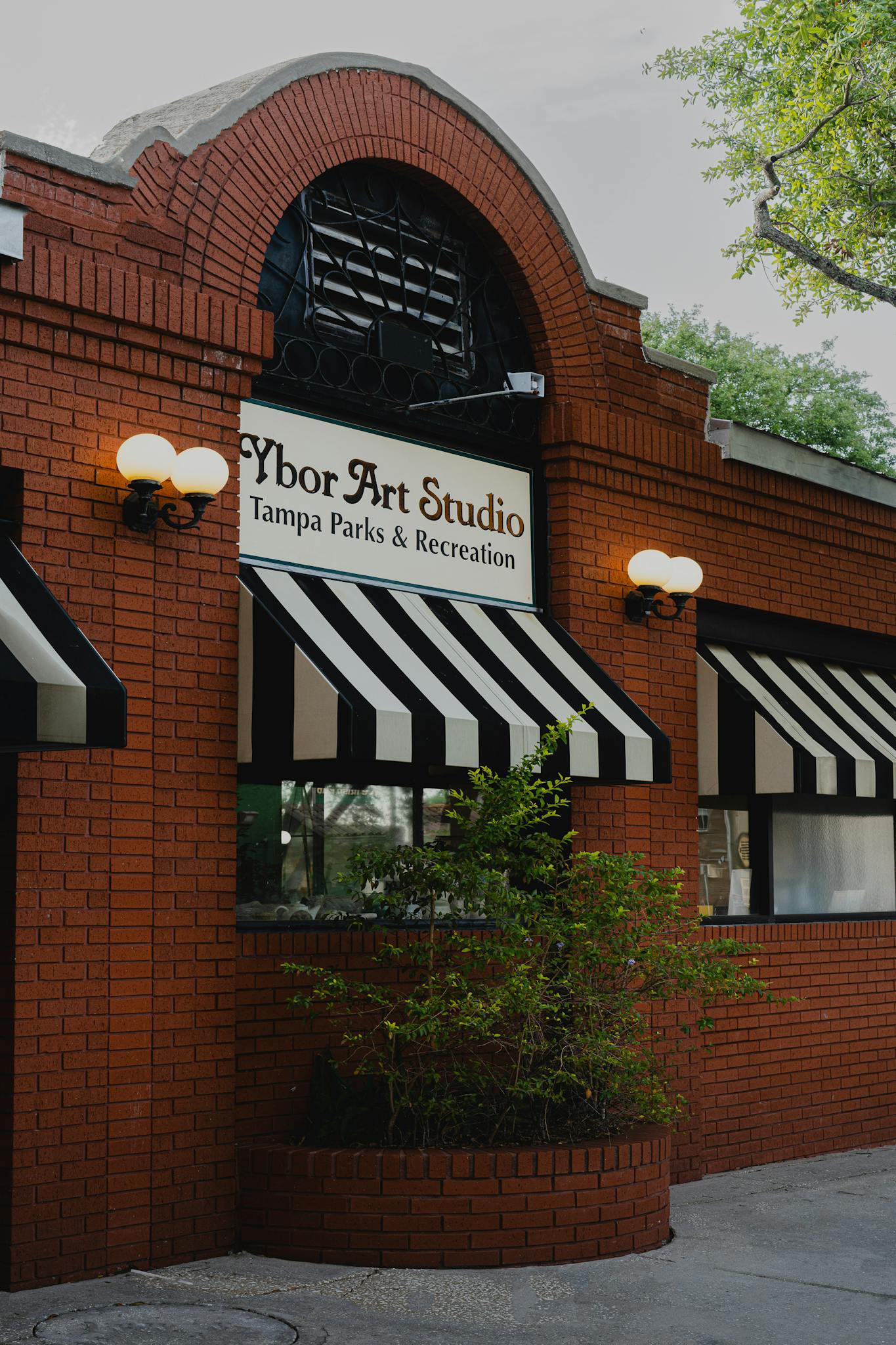 Exterior view of Ybor Art Studio in Tampa, showcasing its classic brick facade and striped awnings.